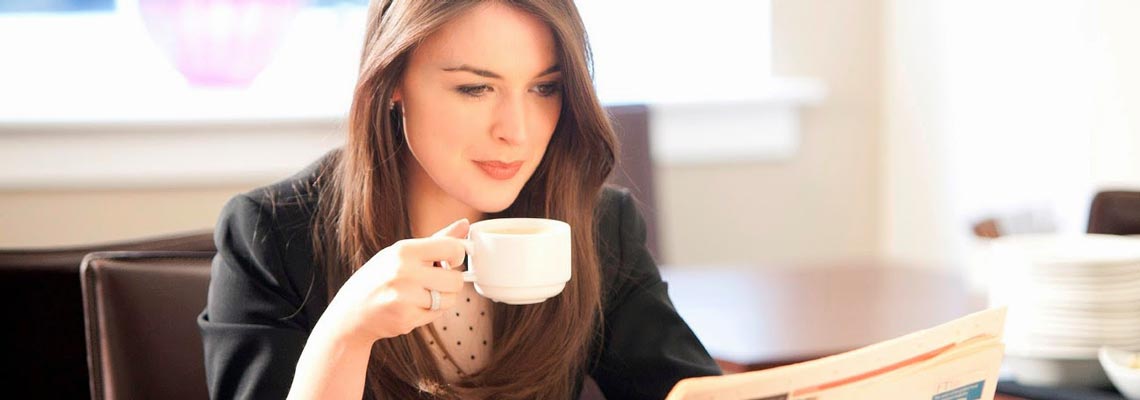 attractive corporate lady enjoying coffee and reading newspaper