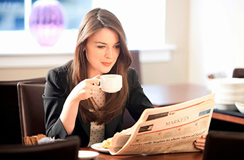 corporate lady enjoying coffee and reading newspaper