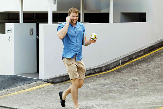 man walkiong with coffee cup advertising cup in hand