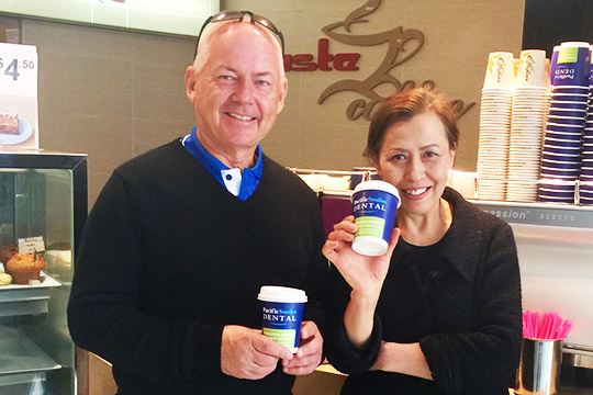 coffee cup advertising in action couple holding pacific smiles dental coffee cups