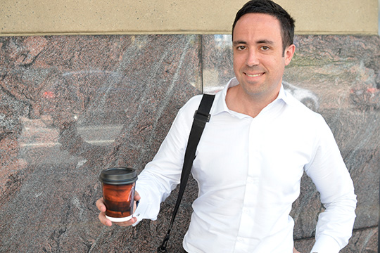 corporate professional man holding university of newcastle coffee cup advertising